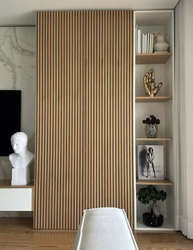 Full-height oak slat panelling beside a niche of styled shelves and a marble wall