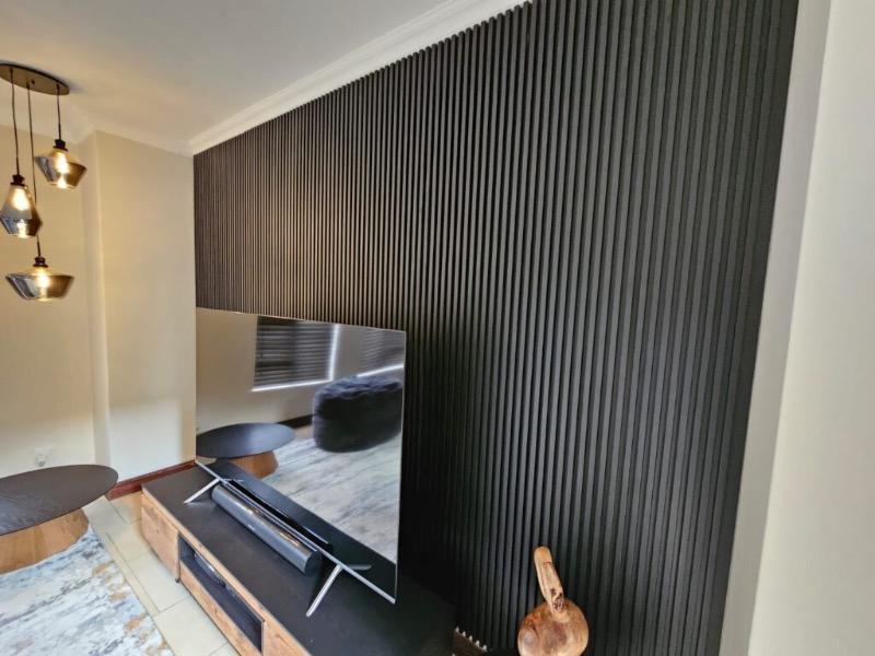 Charcoal slat panelling filling a living-room wall behind a wall-mounted TV and media unit